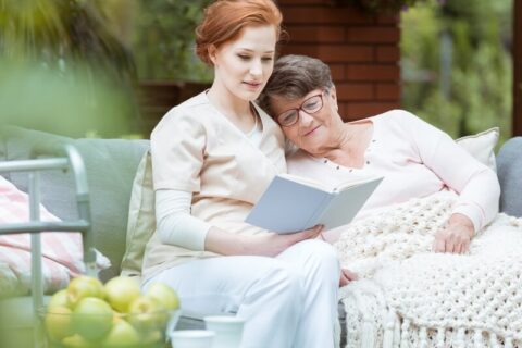 hospice volunteer reading to a patient in a garden