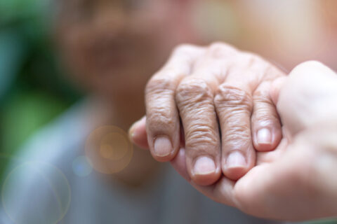 Close-up of a caregiver holding a hospice patient's hand in Portland, OR