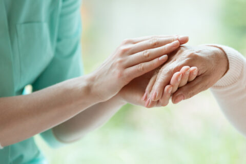 Young hospice worker massaging a hospice patient's hand in Portland, OR