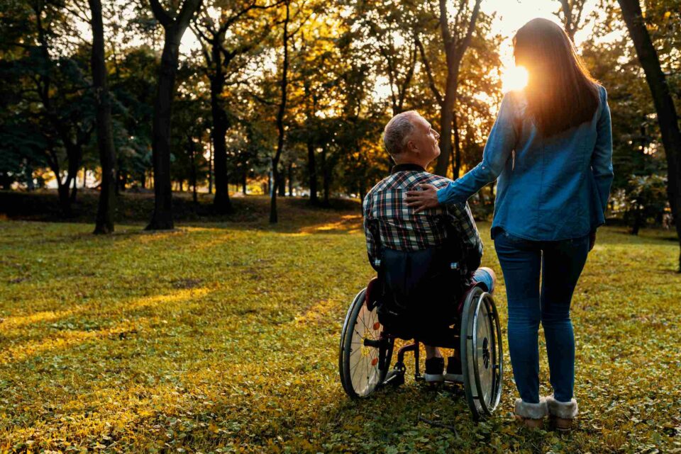 Caregiver offers quiet support to wheelchair user during pastoral care visit in Portland, OR.